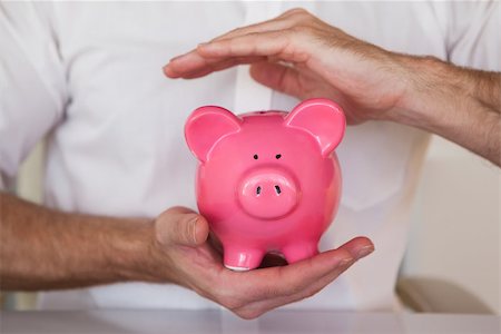 simsearch:6108-05874791,k - Casual businessman holding piggy bank in his office Photographie de stock - Aubaine LD & Abonnement, Code: 400-07662879