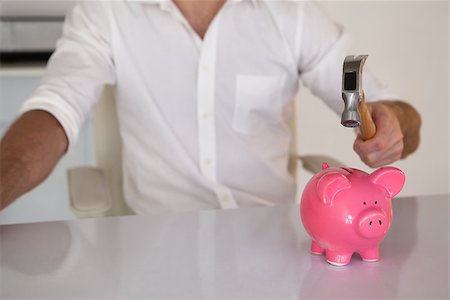 Casual businessman breaking piggy bank with hammer in his office Stock Photo - Budget Royalty-Free & Subscription, Code: 400-07662873