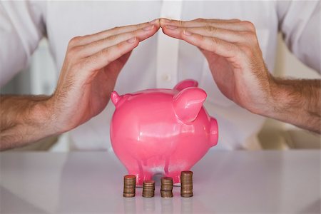 simsearch:400-05715051,k - Casual businessman sheltering piggy bank and coins in his office Fotografie stock - Microstock e Abbonamento, Codice: 400-07662880