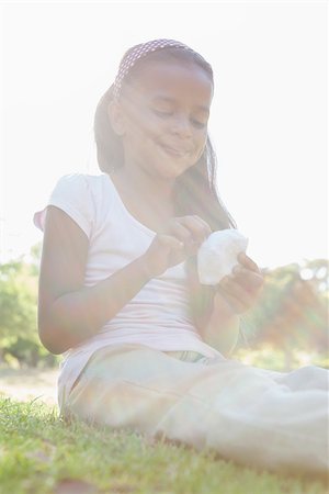 simsearch:400-06890095,k - Little girl sitting on grass eating on a sunny day Stock Photo - Budget Royalty-Free & Subscription, Code: 400-07663669