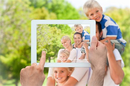 family tablet pc - Hand holding tablet pc showing happy family in the park Photographie de stock - Aubaine LD & Abonnement, Code: 400-07663997