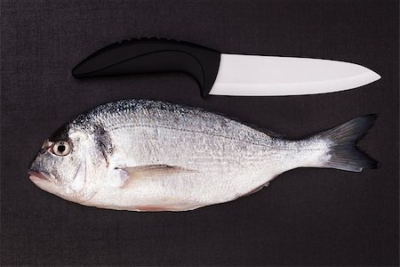 simsearch:400-07776969,k - Delicious sea bram fish with black and white ceramic knife isolated on dark background. Luxurious culinary seafood cooking background. Foto de stock - Super Valor sin royalties y Suscripción, Código: 400-07677161