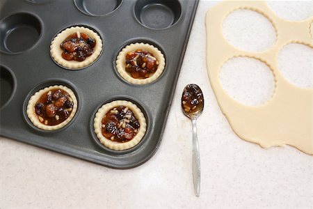 simsearch:400-06693299,k - Making mince pies in the kitchen - filled pastry cases, mincemeat, dough scraps and teaspoon Stockbilder - Microstock & Abonnement, Bildnummer: 400-07677939