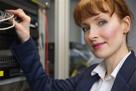 simsearch:400-07684490,k - Pretty computer technician smiling at camera while fixing server in large data center Foto de stock - Super Valor sin royalties y Suscripción, Código: 400-07684385