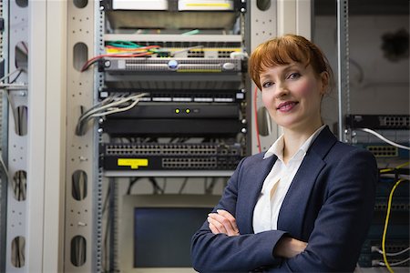 Pretty computer technician smiling at camera while fixing server in large data center Stock Photo - Budget Royalty-Free & Subscription, Code: 400-07684386