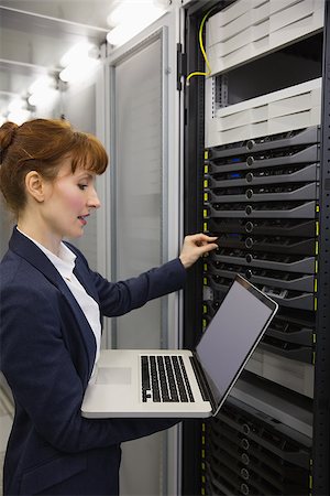 Pretty technician using laptop while working on servers in large data center Stock Photo - Budget Royalty-Free & Subscription, Code: 400-07684414
