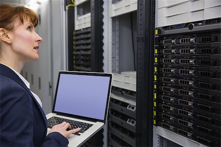 Pretty technician using laptop while working on servers in large data center Stock Photo - Budget Royalty-Free & Subscription, Code: 400-07684411