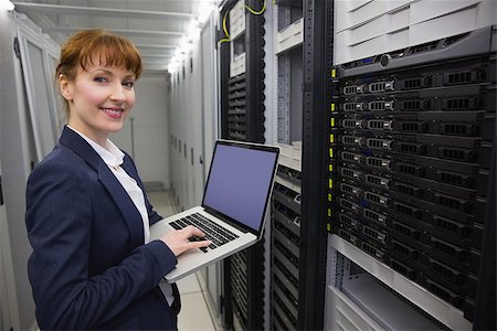Pretty technician using laptop while working on servers in large data center Stock Photo - Budget Royalty-Free & Subscription, Code: 400-07684413