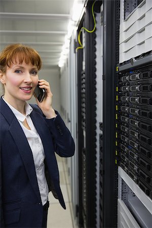 Smiling technician talking on phone while looking at server in large data center Stock Photo - Budget Royalty-Free & Subscription, Code: 400-07684425