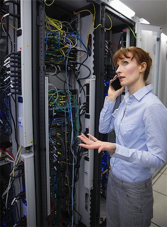 Technician talking on phone while analysing server in large data center Stock Photo - Budget Royalty-Free & Subscription, Code: 400-07684485