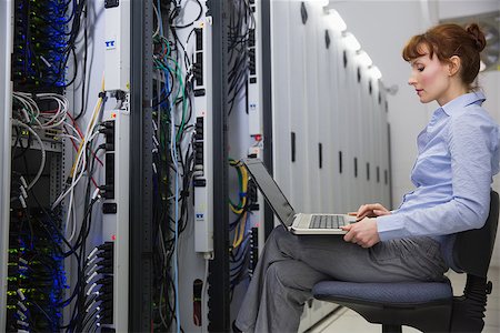 simsearch:400-07684490,k - Technician sitting on swivel chair using laptop to diagnose servers in large data center Foto de stock - Super Valor sin royalties y Suscripción, Código: 400-07684503