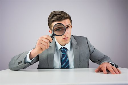 simsearch:400-04861869,k - Businessman sitting at desk with magnifying glass on grey background Foto de stock - Royalty-Free Super Valor e Assinatura, Número: 400-07684565