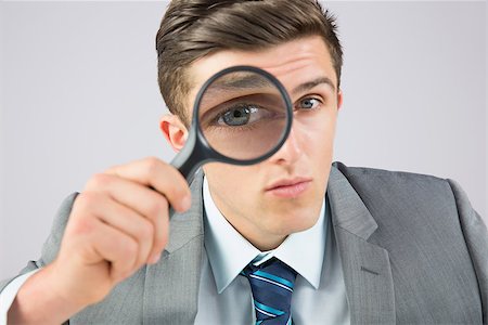 simsearch:400-04861869,k - Businessman looking through magnifying glass on grey background Foto de stock - Royalty-Free Super Valor e Assinatura, Número: 400-07684566