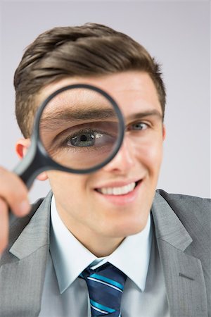 simsearch:400-04861869,k - Businessman looking through magnifying glass on grey background Foto de stock - Royalty-Free Super Valor e Assinatura, Número: 400-07684567