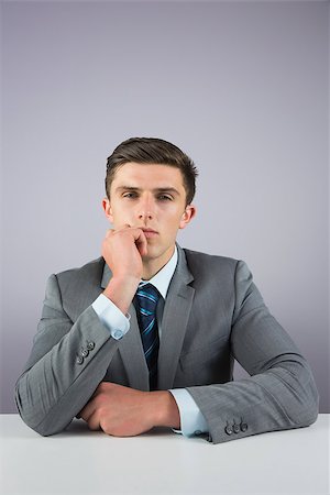 simsearch:400-07275251,k - Serious businessman sitting at desk on grey background Stock Photo - Budget Royalty-Free & Subscription, Code: 400-07684560