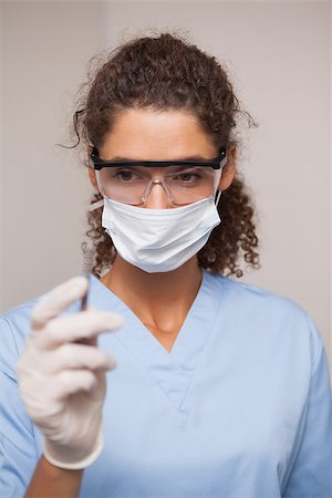 simsearch:400-07941454,k - Dentist in surgical mask and scrubs holding tool at the dental clinic Stockbilder - Microstock & Abonnement, Bildnummer: 400-07684834