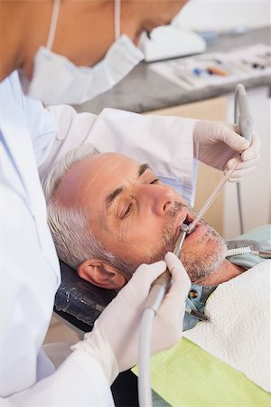 dental work - Dentist examining a patients teeth in the dentists chair at the dental clinic Stock Photo - Budget Royalty-Free & Subscription, Code: 400-07684846