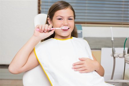 dentist bib girl - Little girl holding toothbrush in dentists chair at the dental clinic Photographie de stock - Aubaine LD & Abonnement, Code: 400-07684896