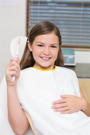 dentist bib girl - Little girl holding toothbrush in dentists chair at the dental clinic Photographie de stock - Aubaine LD & Abonnement, Code: 400-07684897