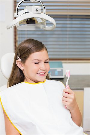 dentist bib girl - Little girl holding toothbrush in dentists chair at the dental clinic Photographie de stock - Aubaine LD & Abonnement, Code: 400-07684898