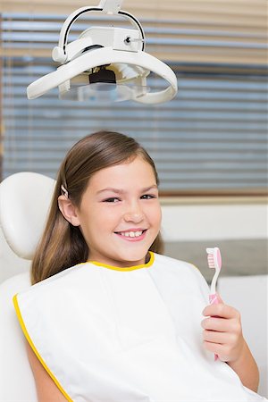 dentist bib girl - Little girl holding toothbrush in dentists chair at the dental clinic Stock Photo - Budget Royalty-Free & Subscription, Code: 400-07684899