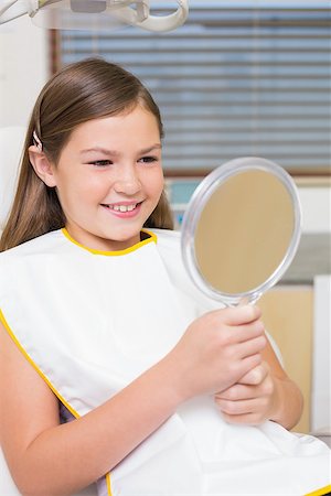 dentist bib girl - Little girl holding mirror in dentists chair at the dental clinic Stock Photo - Budget Royalty-Free & Subscription, Code: 400-07684901