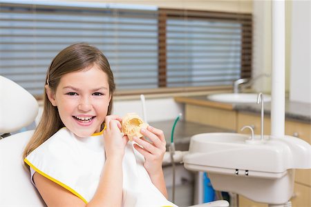 dental bib - Little girl sitting in dentists chair holding model teeth at the dental clinic Stock Photo - Budget Royalty-Free & Subscription, Code: 400-07684919