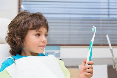 simsearch:400-07684901,k - Little boy in dentists chair holding toothrbrush at the dental clinic Stock Photo - Budget Royalty-Free & Subscription, Code: 400-07684962