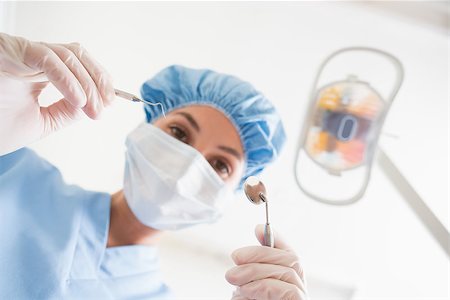 female with dental tools at work - Dentist in surgical mask and cap holding dental tools over patient at the dental clinic Stock Photo - Budget Royalty-Free & Subscription, Code: 400-07685085