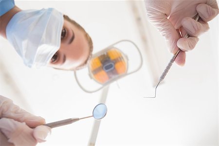 female with dental tools at work - Dentist in surgical mask holding dental tools over patient at the dental clinic Stock Photo - Budget Royalty-Free & Subscription, Code: 400-07685096