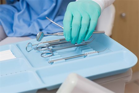 dentistry tray - Dentist in blue scrubs picking up tools at the dental clinic Stock Photo - Budget Royalty-Free & Subscription, Code: 400-07685105