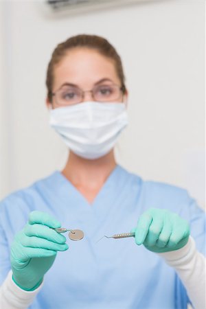 simsearch:400-07941454,k - Dentist in blue scrubs holding tools looking at camera at the dental clinic Stockbilder - Microstock & Abonnement, Bildnummer: 400-07685110