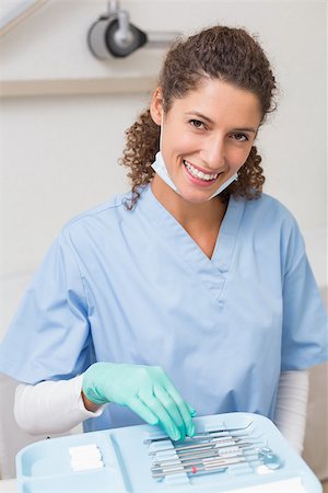 female with dental tools at work - Dentist smiling at camera while picking up tools at the dental clinic Stock Photo - Budget Royalty-Free & Subscription, Code: 400-07685156