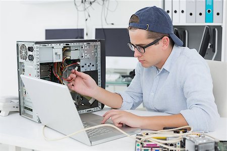 simsearch:400-05244427,k - Computer engineer working on broken console with laptop in his office Stock Photo - Budget Royalty-Free & Subscription, Code: 400-07685429