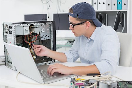 simsearch:400-05244427,k - Computer engineer working on broken console with laptop in his office Stock Photo - Budget Royalty-Free & Subscription, Code: 400-07685430