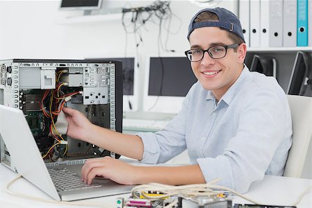 simsearch:400-05244427,k - Computer engineer working on broken console with laptop in his office Stock Photo - Budget Royalty-Free & Subscription, Code: 400-07685431