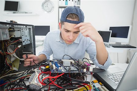 simsearch:400-05244427,k - Computer engineer working on broken console with laptop in his office Stock Photo - Budget Royalty-Free & Subscription, Code: 400-07685454