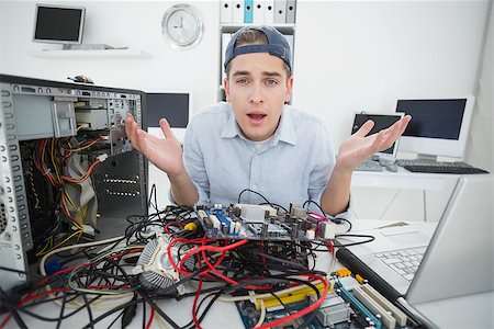 simsearch:400-05244427,k - Confused computer engineer working on broken console with laptop in his office Stock Photo - Budget Royalty-Free & Subscription, Code: 400-07685455