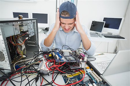 simsearch:400-05244427,k - Confused computer engineer working on broken console with laptop in his office Stock Photo - Budget Royalty-Free & Subscription, Code: 400-07685456