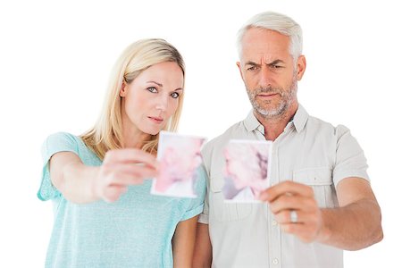 simsearch:400-07726420,k - Unhappy couple holding two halves of torn photograph on white background Fotografie stock - Microstock e Abbonamento, Codice: 400-07685924