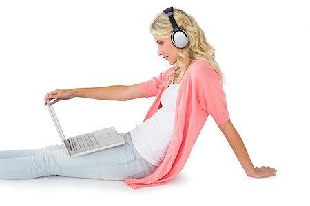 simsearch:400-06690896,k - Pretty young blonde sitting using laptop listening to music on white background Stock Photo - Budget Royalty-Free & Subscription, Code: 400-07686386
