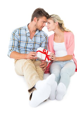 simsearch:400-07726699,k - Attractive young couple sitting holding a gift on white background Foto de stock - Super Valor sin royalties y Suscripción, Código: 400-07686434