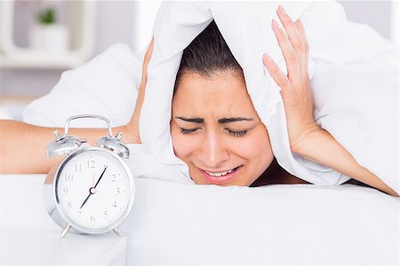 Woman covering ears with sheet in bed and alarm clock on side table Stock Photo - Budget Royalty-Free & Subscription, Code: 400-07687198