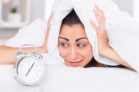 Woman covering ears with sheet in bed and alarm clock on side table Stock Photo - Budget Royalty-Free & Subscription, Code: 400-07687199