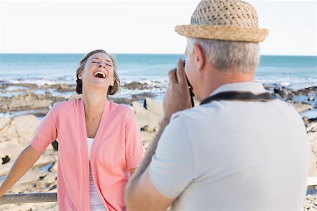 simsearch:693-03707681,k - Happy casual man taking a photo of partner by the sea on a sunny day Foto de stock - Royalty-Free Super Valor e Assinatura, Número: 400-07687578