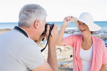 simsearch:693-03707681,k - Happy casual man taking a photo of partner by the sea on a sunny day Foto de stock - Royalty-Free Super Valor e Assinatura, Número: 400-07687581