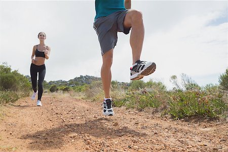 simsearch:400-07688341,k - Low angle view of fit young couple running on countryside road Stock Photo - Budget Royalty-Free & Subscription, Code: 400-07688440