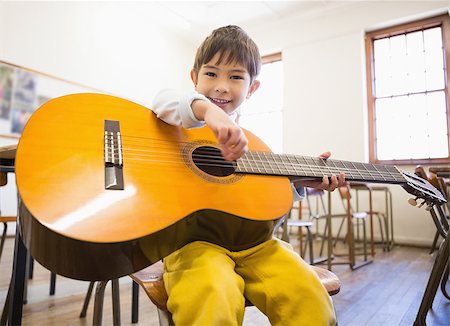 simsearch:400-07991069,k - Cute pupil playing guitar in classroom at the elementary school Foto de stock - Royalty-Free Super Valor e Assinatura, Número: 400-07688887