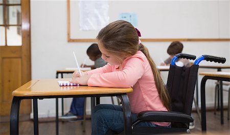 simsearch:400-07991158,k - Disabled pupil writing at desk in classroom at the elementary school Stock Photo - Budget Royalty-Free & Subscription, Code: 400-07688998