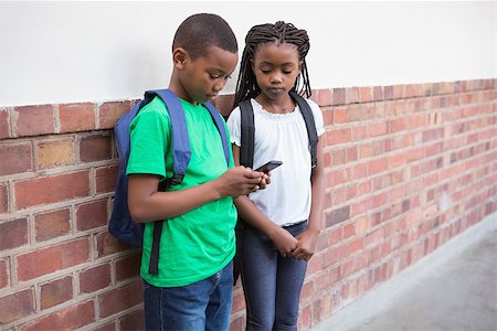 simsearch:400-07991158,k - Cute pupils looking at smartphone in corridor at the elementary school Stock Photo - Budget Royalty-Free & Subscription, Code: 400-07689053